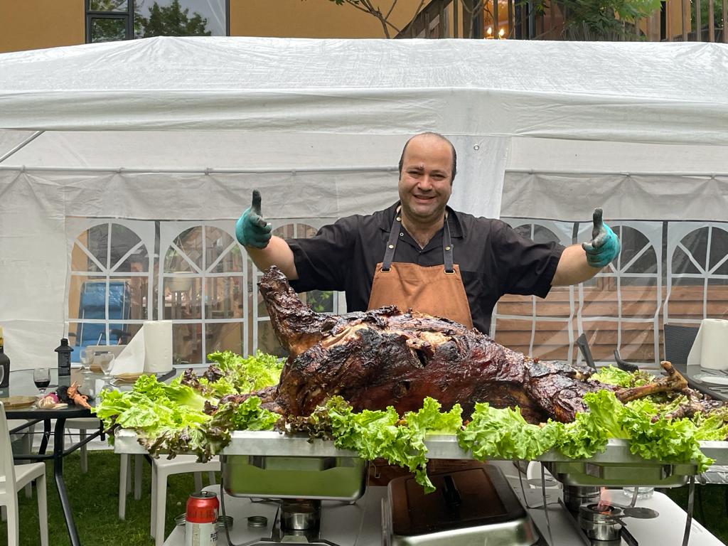 Chef présentant un agneau rôti entier lors d'un événement extérieur du Café Restaurant L